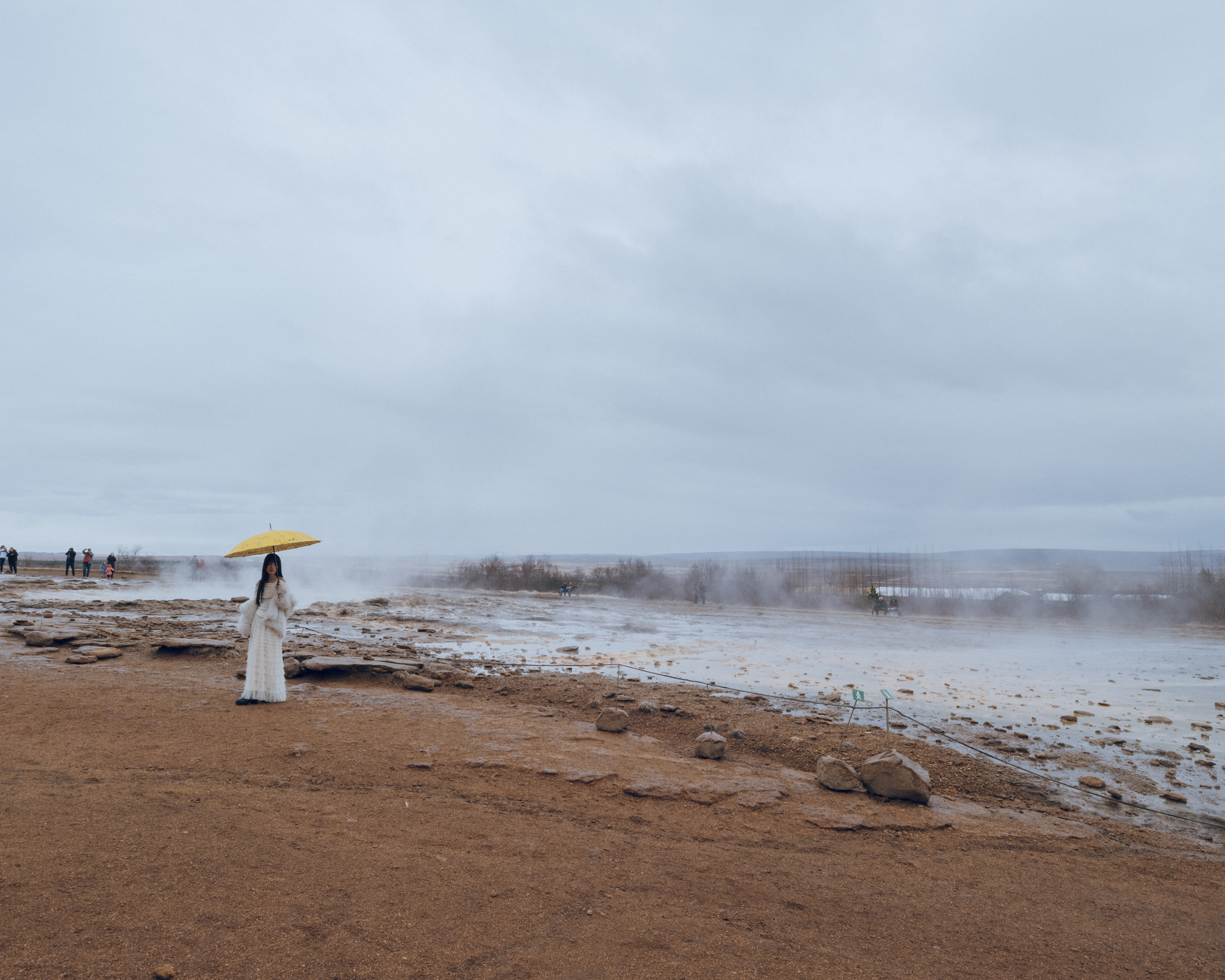 Girl with Umbrella at Geysir Strokkur Blesi, Haukadalur Valley, Iceland: A playful moment amidst geothermal wonders