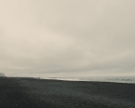 The beach with distinctive rock formations in the background is Reynisfjara, located on Iceland’s southern coast. Known for its black sand, the beach is a famous landmark near the village of Vík. The basalt columns and rock formations, called Reynisdrangar, are iconic features of this area.